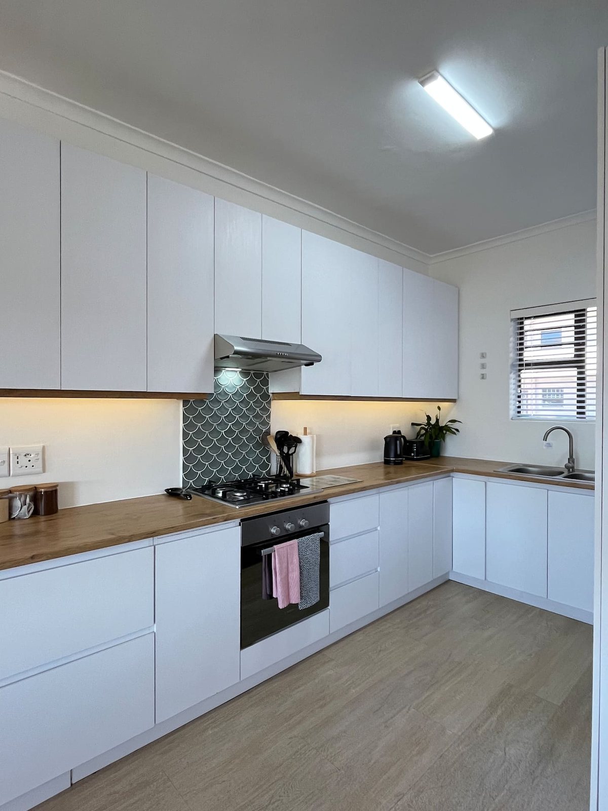 Kitchen at Atlantic Apartment with white cabinetry, a gas hob and a scalloped tile splashback