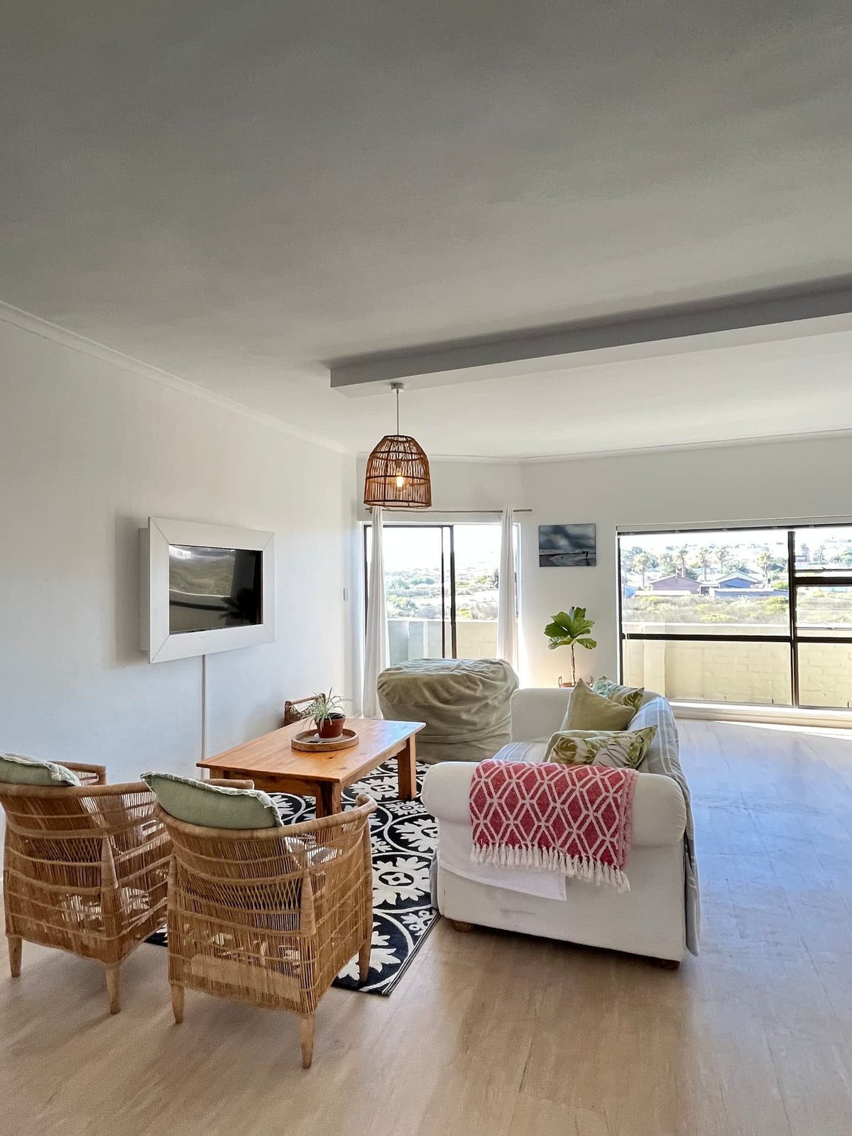 Living room at Atlantic Apartment with a wall-mounted TV, wicker chairs and sliding doors onto the balcony with sea views