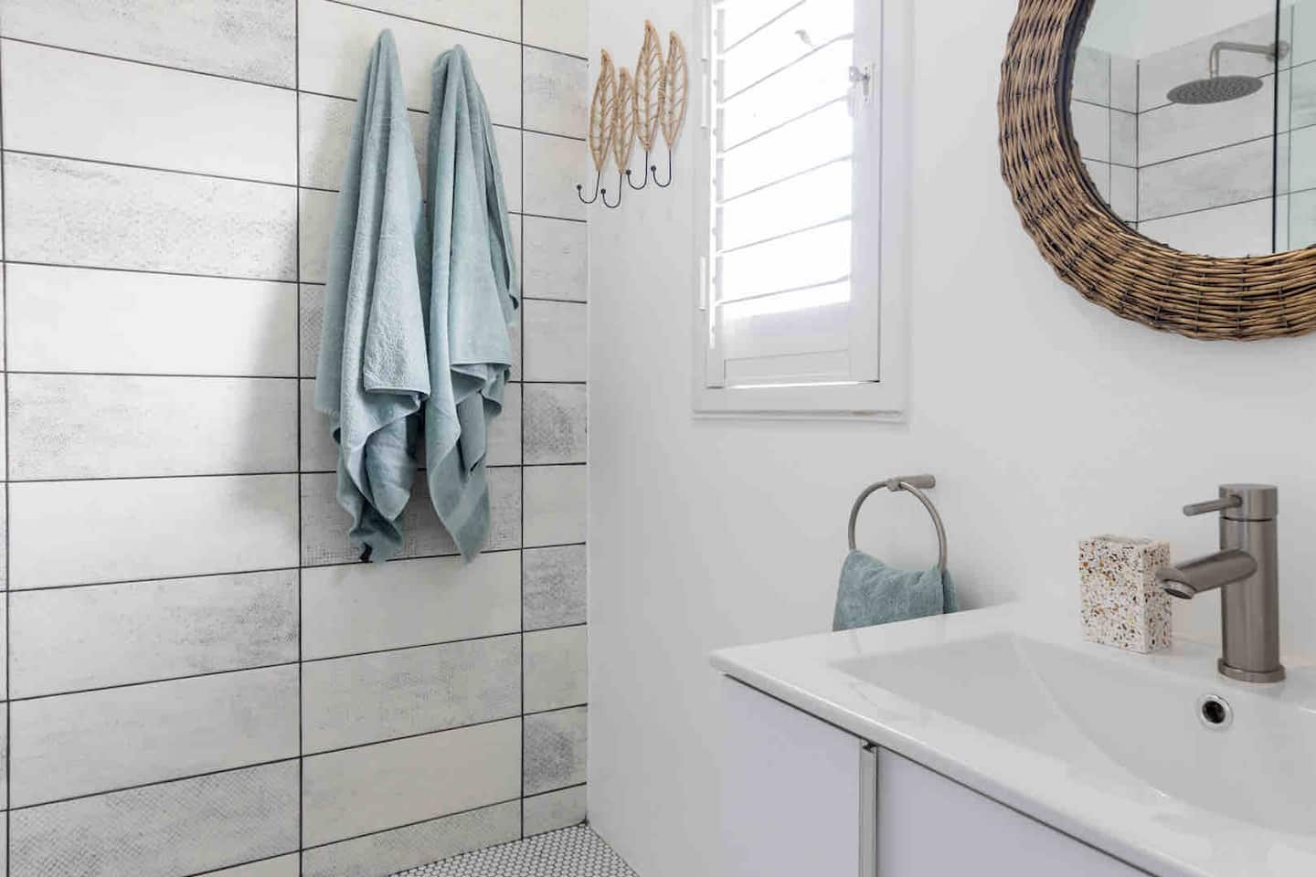 En-suite bathroom at Atlantic Beach Cottage with a walk-in shower and woven mirror