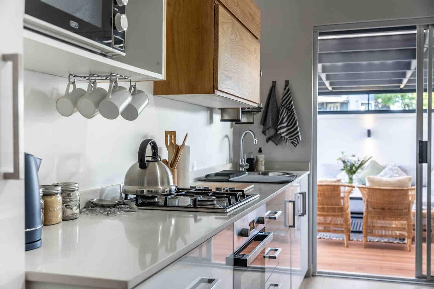 Kitchen at Atlantic Beach Cottage with a gas hob, hanging mugs and a sliding door open to the patio