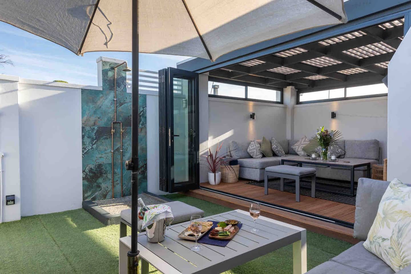 Outdoor shower and braai yard at Atlantic Beach Cottage with lounge seating under a pergola