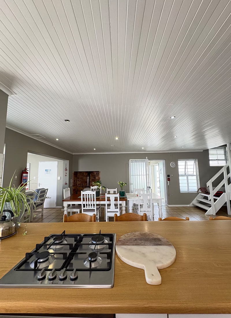Open-plan kitchen and dining area at Atlantic Crew House, with a gas hob on a wooden counter and a long dining table beyond