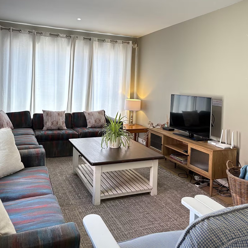 TV lounge at Atlantic Crew House with corner sofas, a coffee table and curtained windows